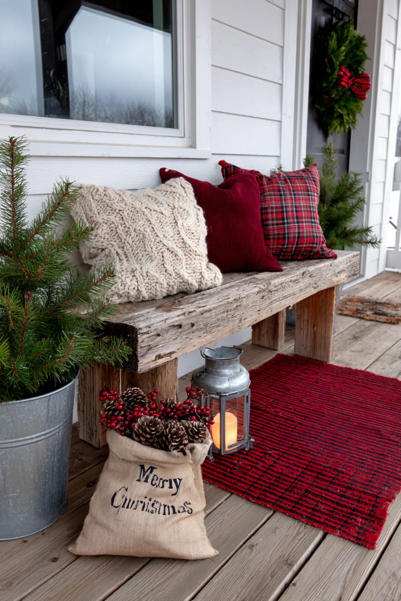 15 Cozy Rustic Christmas Porch Ideas for Country Charm 21 cozy red plaid rug layered beneath a rustic wooden bench and chunky knit pillows 1