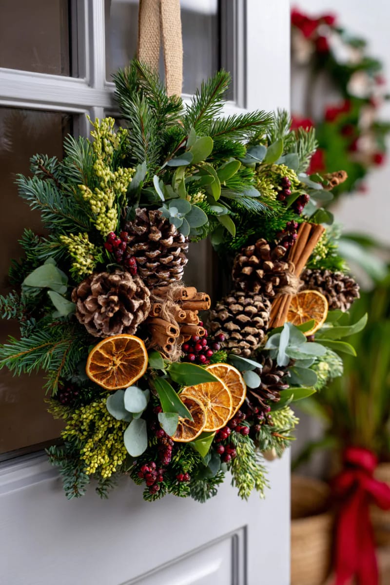 25 Pinecone Christmas Decorations You’ll Want to Keep Up All Winter 12 pinecone wreath with mixed greenery, cinnamon sticks, and dried orange slices 1