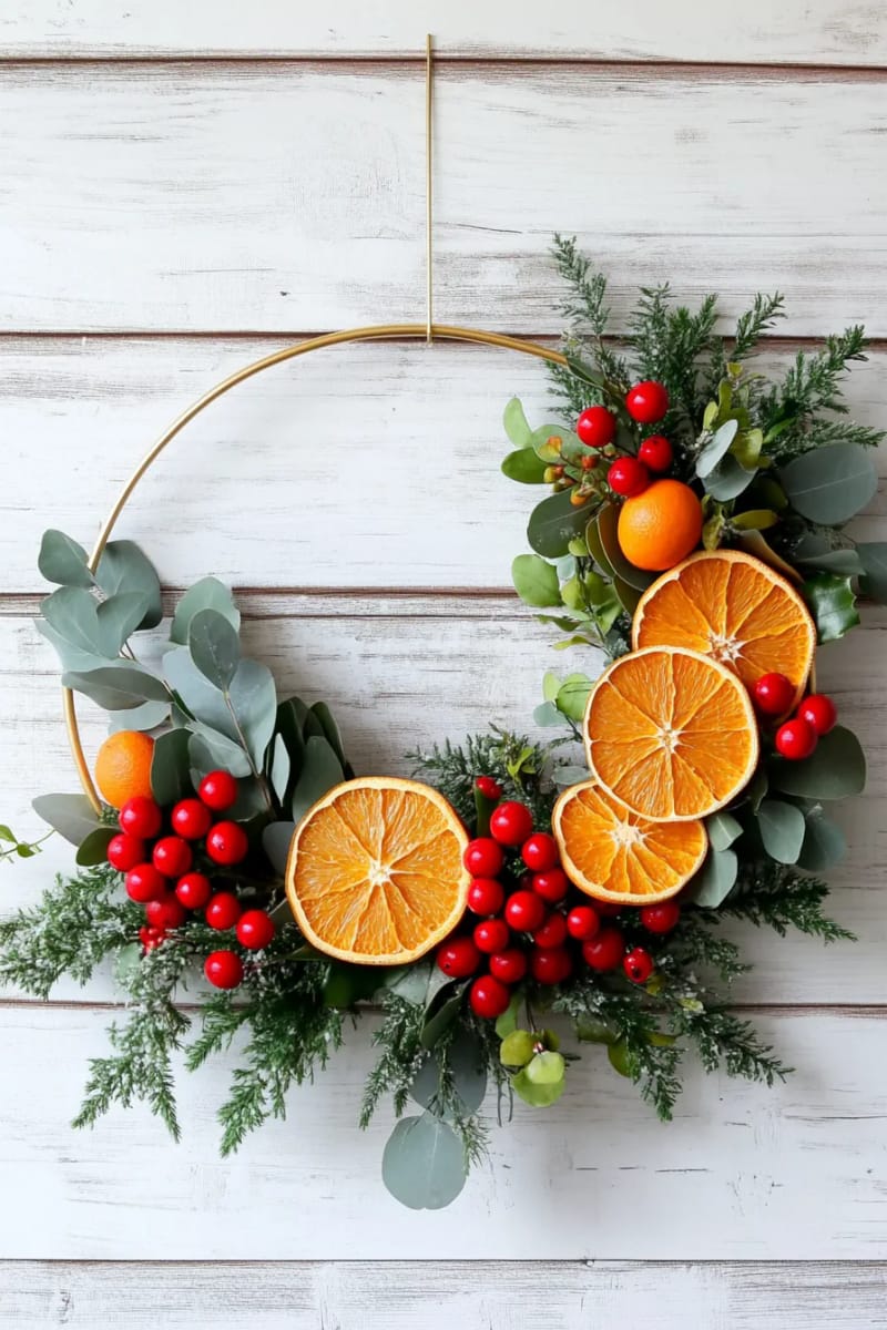 arrange dried oranges and red berries on a wire hoop for a minimalist wreath 1