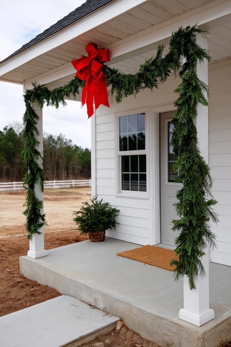 sparse garland on porch pillars with a single, large red bow 1
