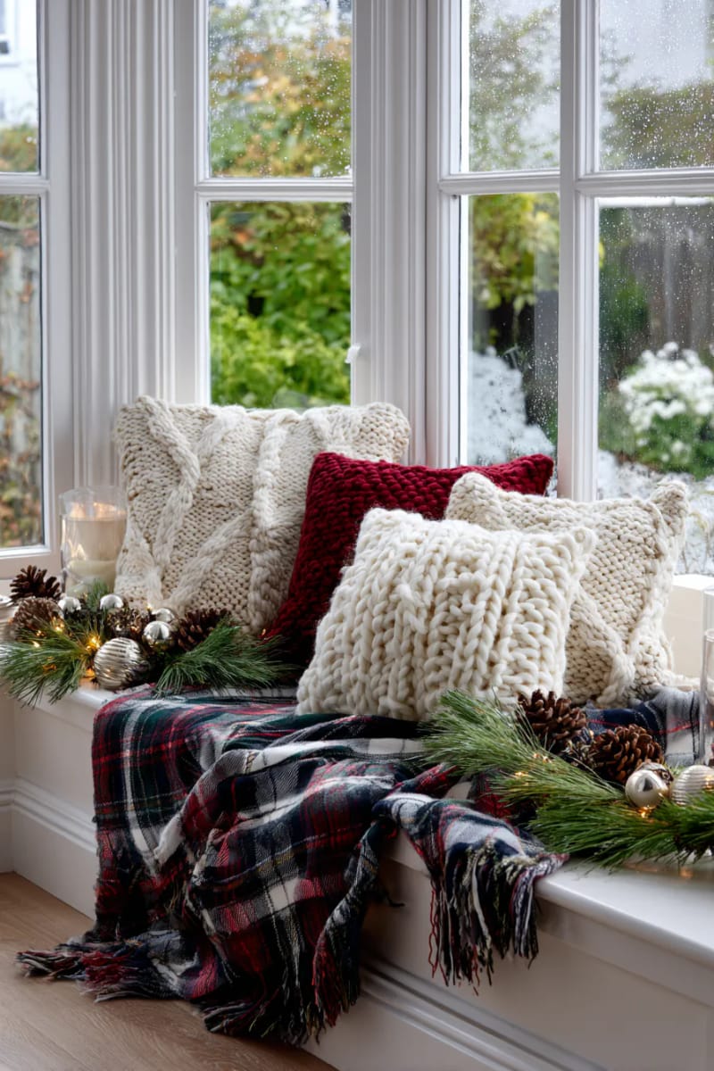 window seat dressed in tartan blankets, pine sprigs, and chunky knit cushions 1