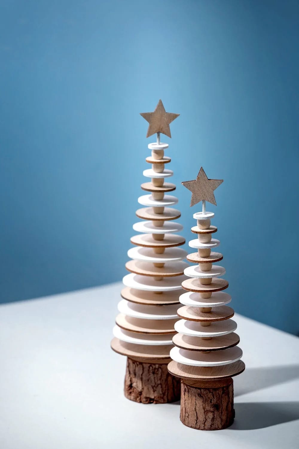 Log Round Christmas Decorations for a Rustic Mantel Without Crowding the Shelf 17 Two handcrafted Christmas tree decorations made from stacked wooden slices with star toppers, set on log round bases, illustrating rustic mantel decor for Christmas without crowding the shelf.