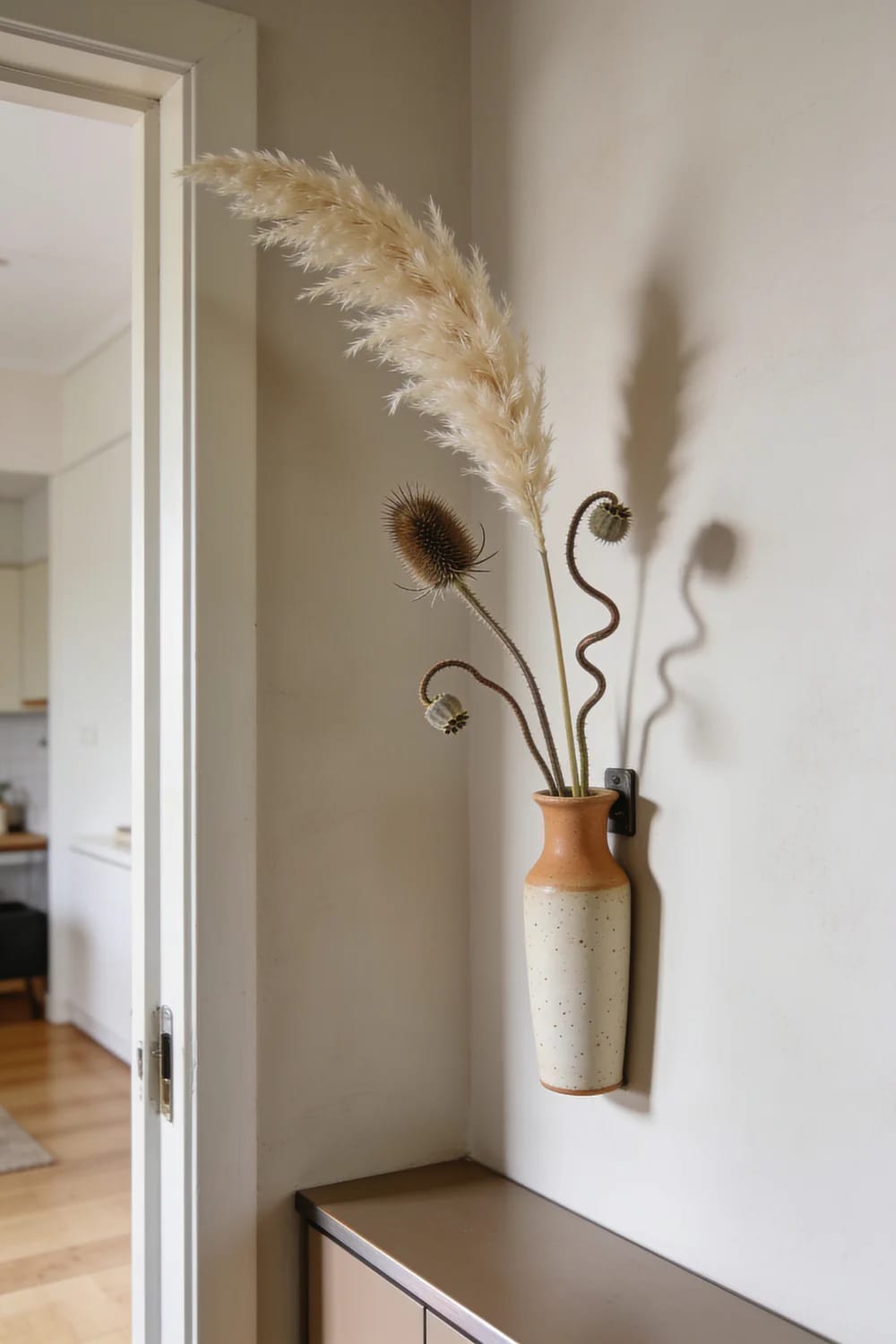 Dried Seedhead and Pampas Winter Arrangements That Don't Read as Leftover Fall 11 a wall vase gets the dried arrangement out of a small apartment's way 1