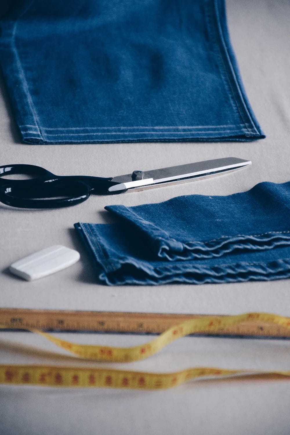 Denim Bucket Bag Cutting Supplies Denim fabric pieces, fabric scissors, a wooden ruler, and measuring tapes arranged for making a denim bucket bag