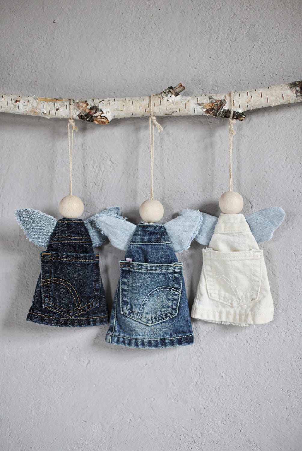 Jean Pocket Christmas Angel Ornaments Three angel ornaments hang from a birch branch, featuring wooden bead heads, denim or white pocket dresses, and light blue fabric wings for jean pocket Christmas ornaments
