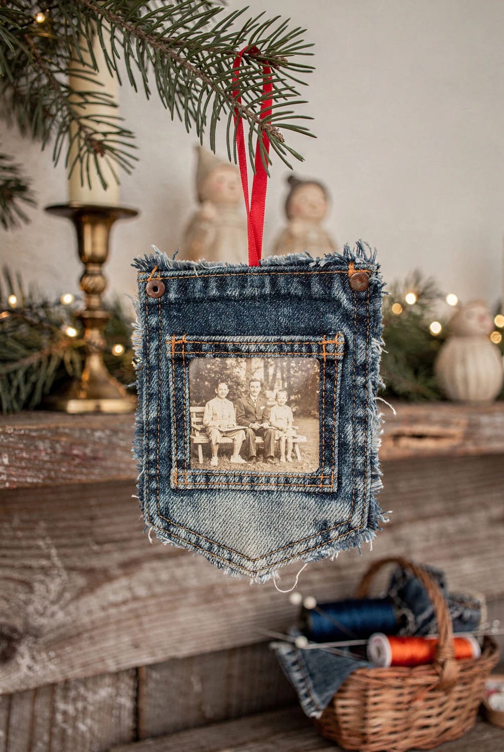 Jean Pocket Christmas Ornament With Photo A fringed denim jean pocket Christmas ornament hangs from a red ribbon, with a sepia family photograph displayed in the pocket against a decorated Christmas tree