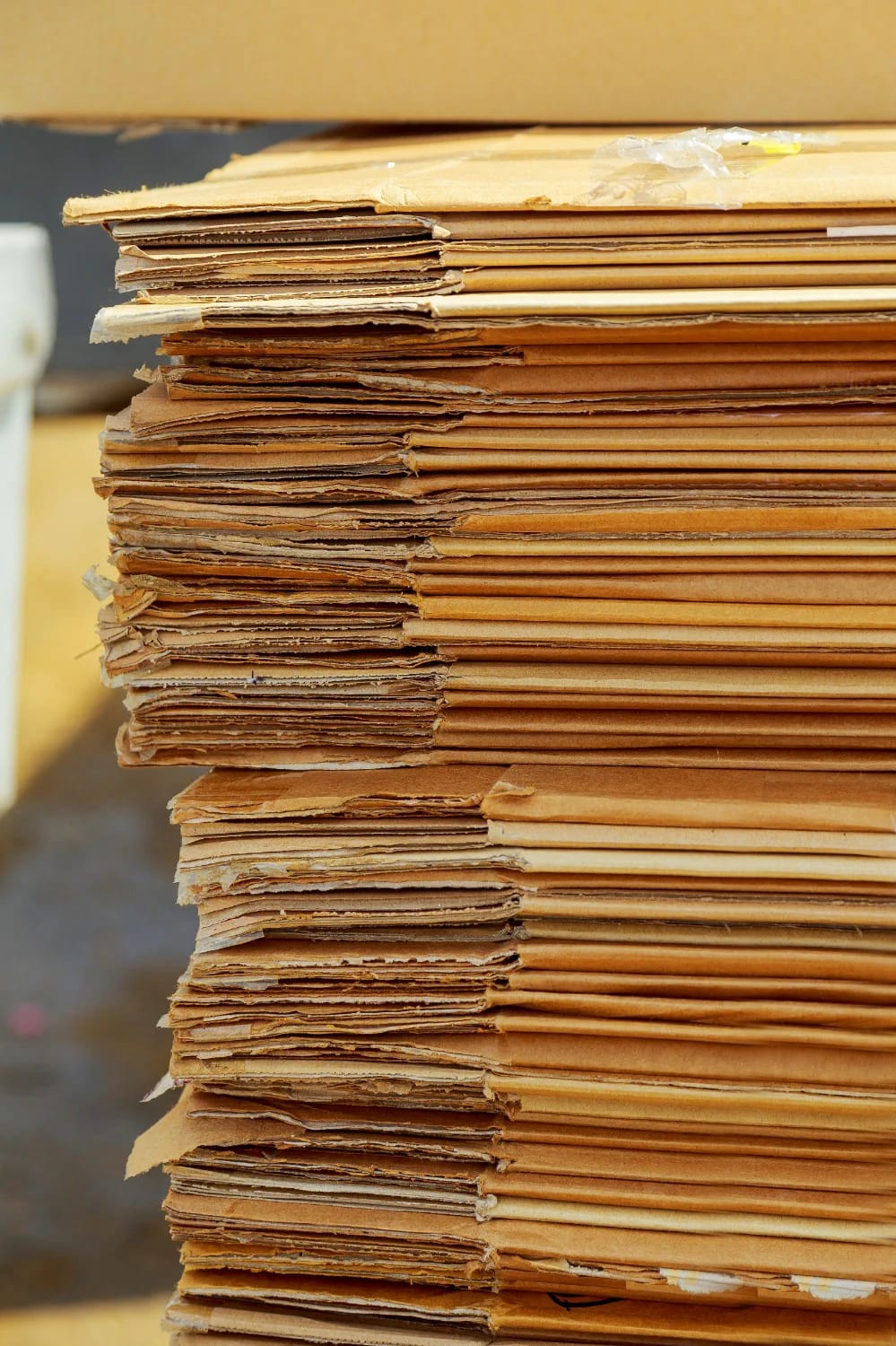 Stack of flattened brown cardboard sheets for building a cardboard castle playhouse from recycled boxes