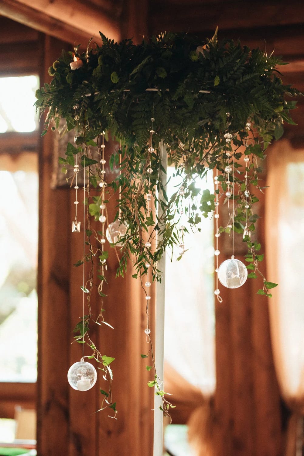 Plastic Bottle Flower Chandelier Party Ceiling A lush hanging greenery chandelier with cascading vines and multiple suspended clear glass-like ornaments, shown indoors beneath a wooden ceiling for a party decoration concept