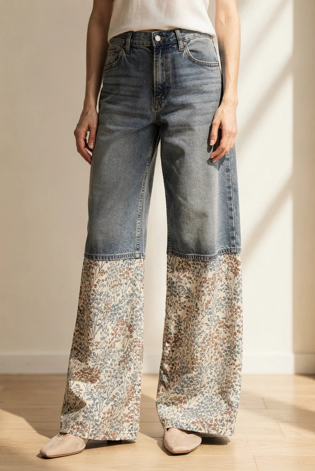 Wide Leg Patchwork Jeans With Floral Panels Model wearing wide-leg jeans with blue denim from the waist to the knees and cream floral cotton panels extending to the floor, paired with a white top and beige flats